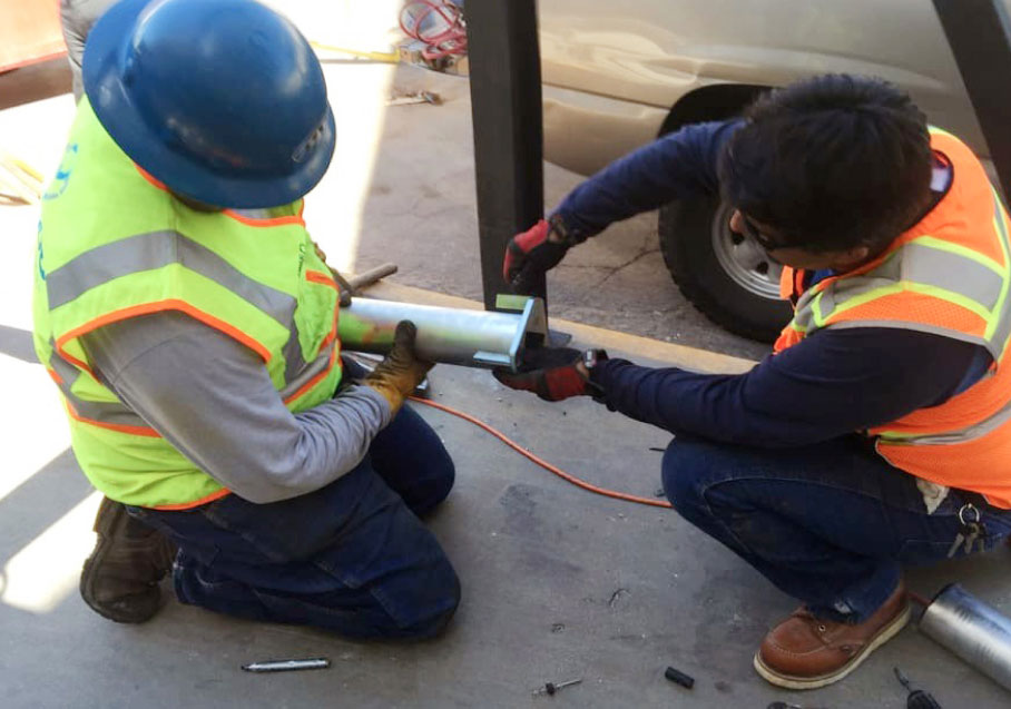 Workers Assembling Metal Pipe on Construction Site